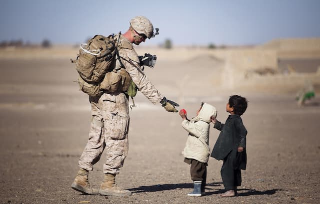 Photo of a little boy giving an apple to a soldier 